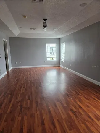 an empty room with wooden floor and windows
