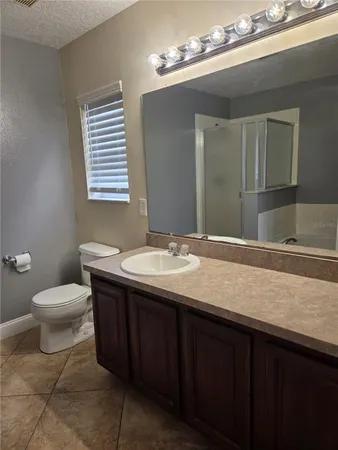 a bathroom with a granite countertop sink a toilet and a mirror
