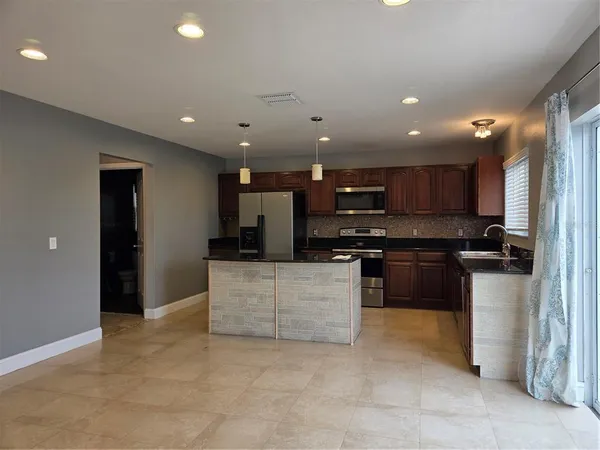 a kitchen with stainless steel appliances kitchen island granite countertop a refrigerator a stove and a sink