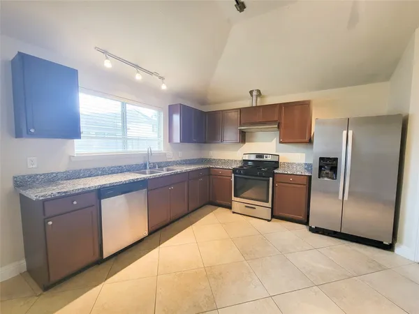 a kitchen with granite countertop a refrigerator sink and cabinets