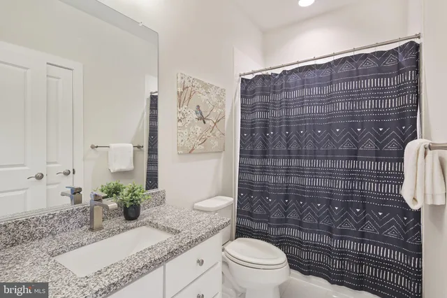 a bathroom with a granite countertop toilet sink and mirror