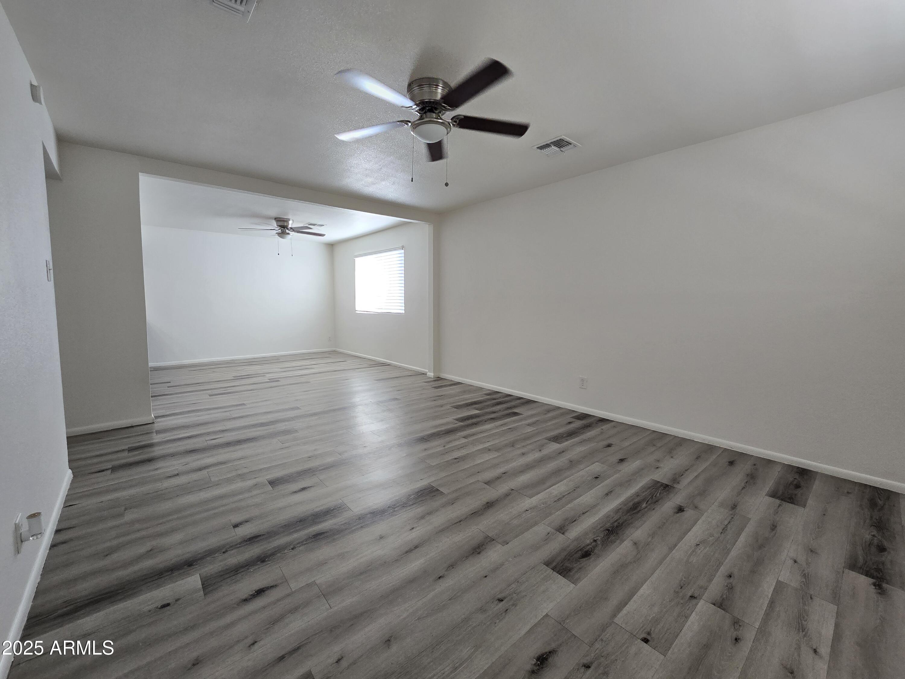 2211 West Pecan Road Phoenix, AZ 85041 - Photo 8 of 21 an empty room with wooden floor and windows