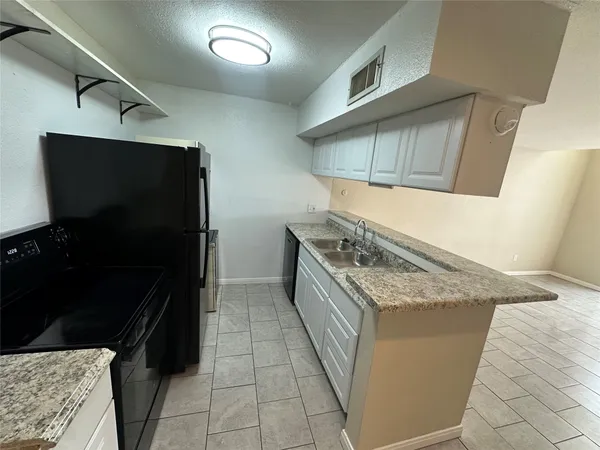 a kitchen with a granite countertop sink and cabinets