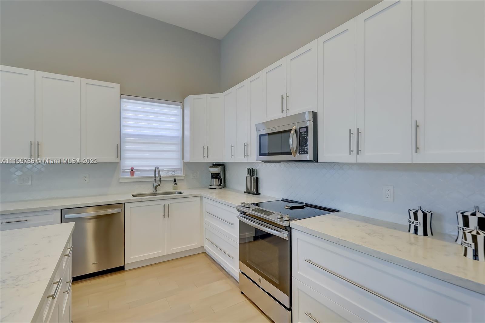 9901 North Abiaca Circle Davie, FL 33328 - Photo 12 of 46 a kitchen with granite countertop white cabinets and white appliances
