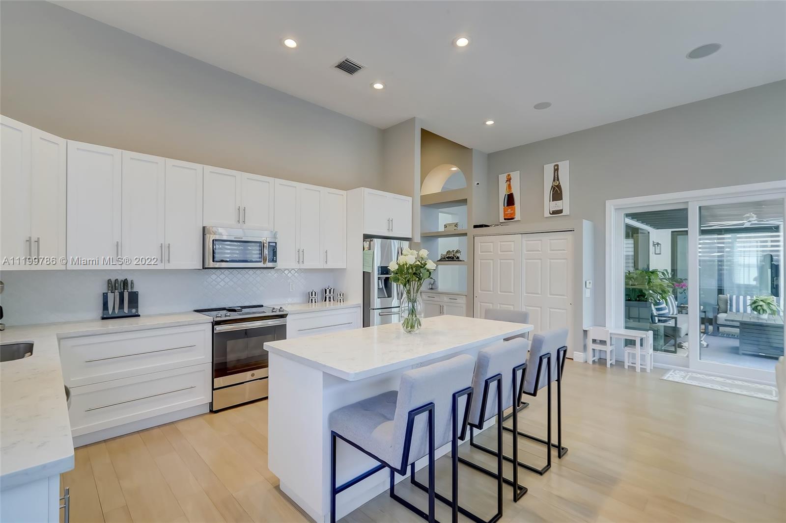 9901 North Abiaca Circle Davie, FL 33328 - Photo 19 of 46 a kitchen with stainless steel appliances kitchen island granite countertop a stove a sink a refrigerator and white cabinets with wooden floor