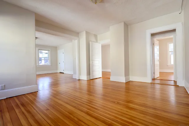 a view of an empty room with wooden floor and a window