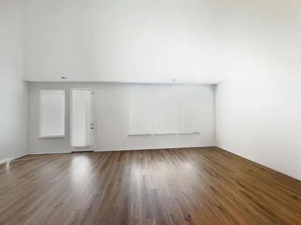 a view of an empty room with wooden floor and windows