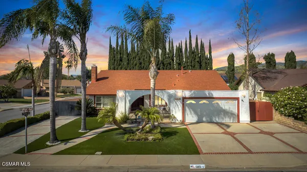 a view of a house with a yard and palm trees