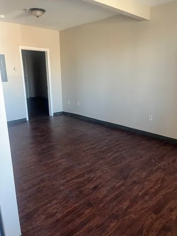 a view of an empty room with wooden floor and closet