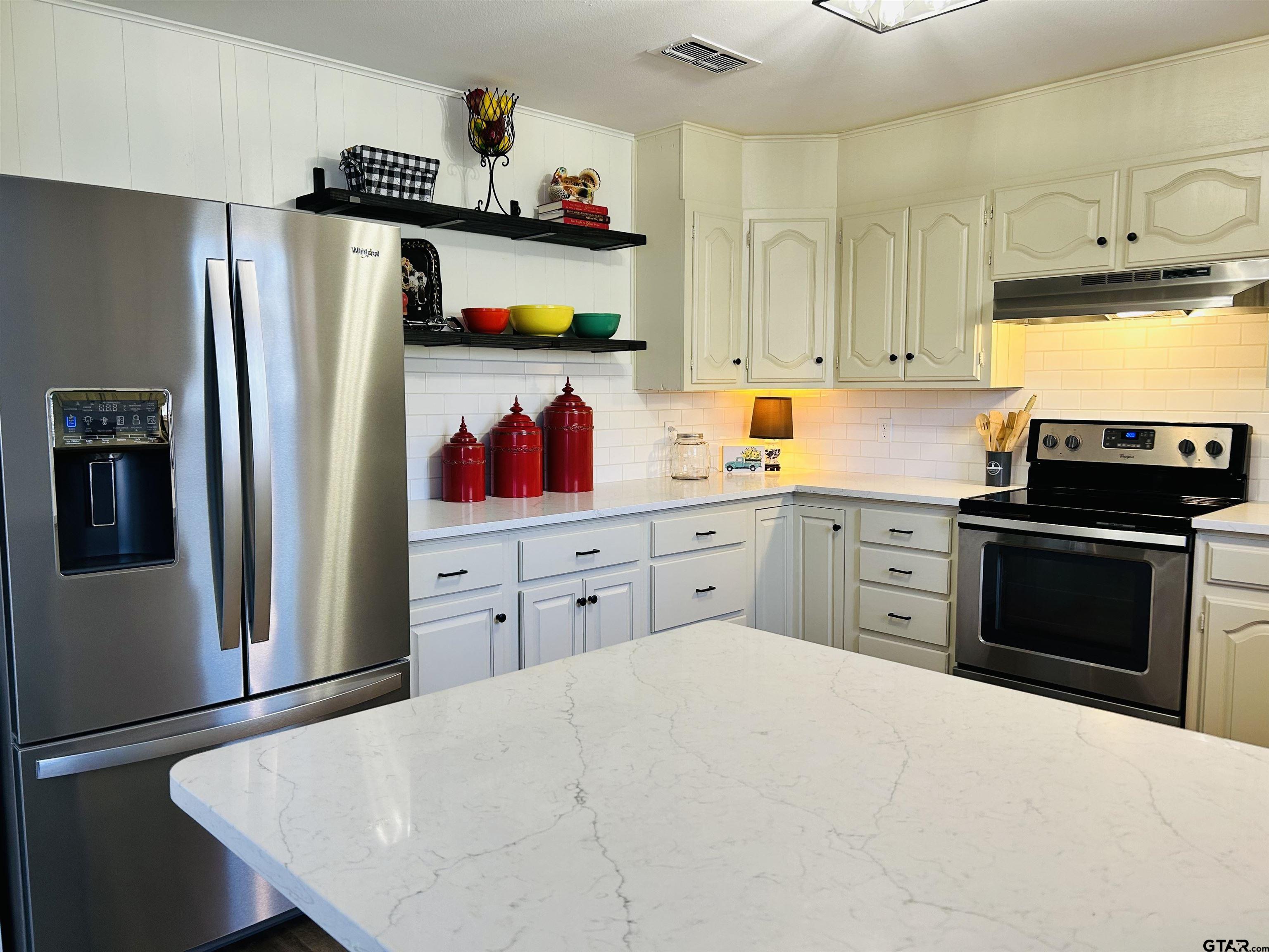 a kitchen with stainless steel appliances a stove refrigerator and cabinets