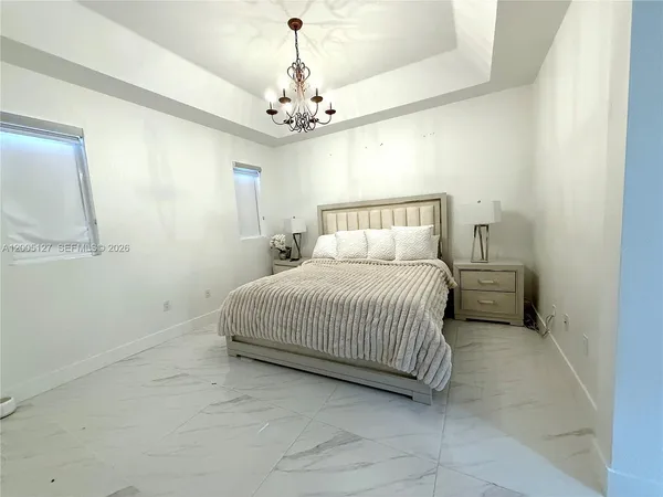 a spacious bedroom with a bed and a chandelier
