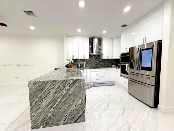 a kitchen with stainless steel appliances granite countertop a refrigerator sink and stove
