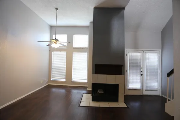 an empty room with wooden floor fireplace and windows