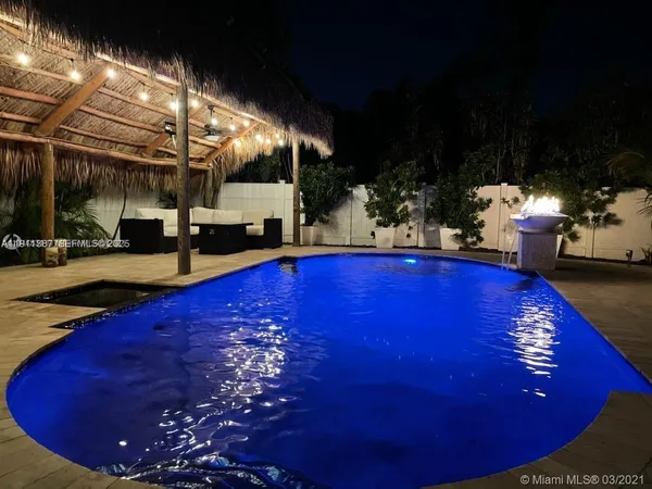 a view of swimming pool with lawn chairs and plants