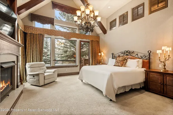 a spacious bedroom with a bed couch chandelier and a large window