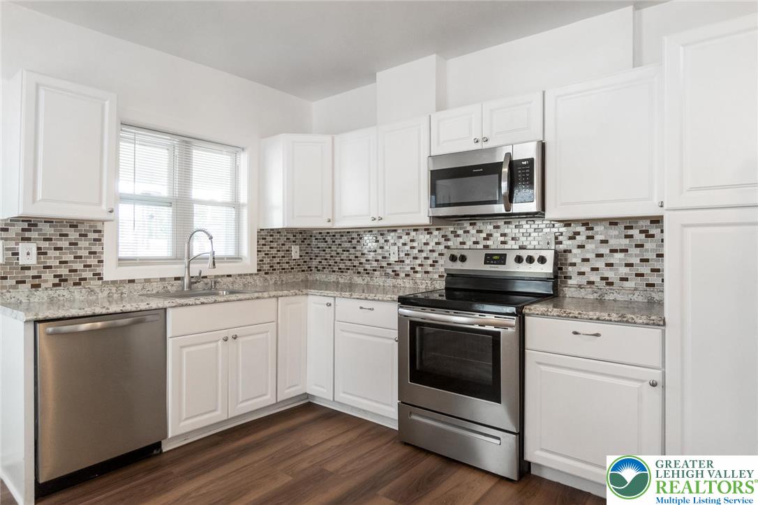 909 South Hall Street Allentown, PA 18103 - Photo 14 of 36 a kitchen with granite countertop white cabinets appliances a sink and a window