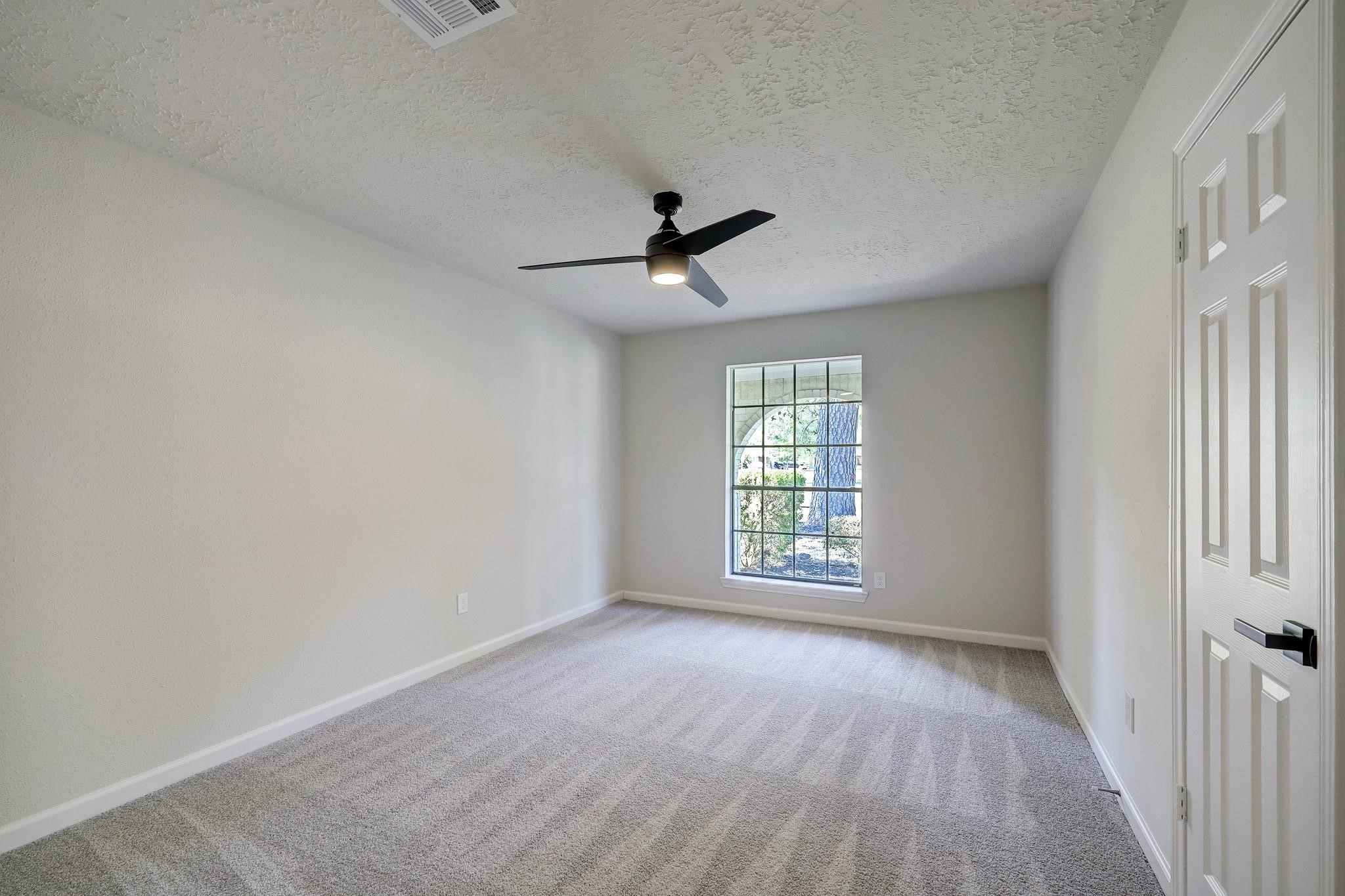 9723 Galston Lane Spring, TX 77379 - Photo 16 of 24 A tranquil bedroom with plush carpeting, a wide window that fills the room with light, and a ceiling fan for year-round comfort. Neutral tones offer a versatile canvas for any décor.