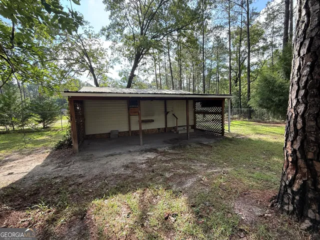 a view of a wooden house with a yard and large trees