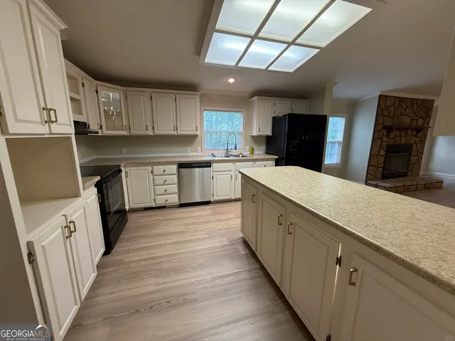 a large kitchen with a large counter top space a sink stainless steel appliances and cabinets