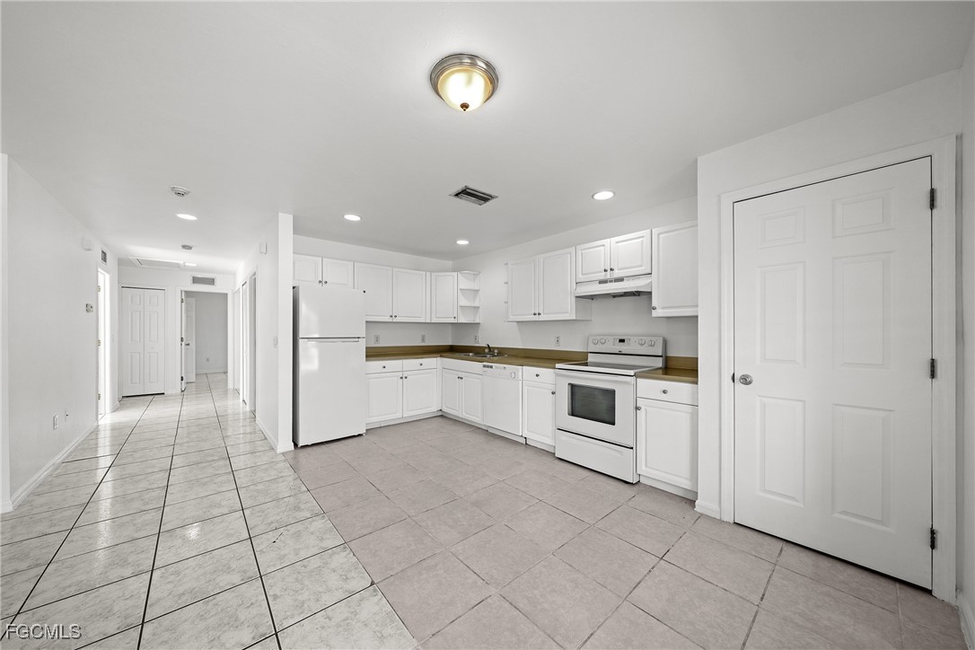 4733-4735 30th Street Southwest Lehigh Acres, FL 33973 - Photo 21 of 43 a large white kitchen with a stove a sink dishwasher and a refrigerator with white cabinets