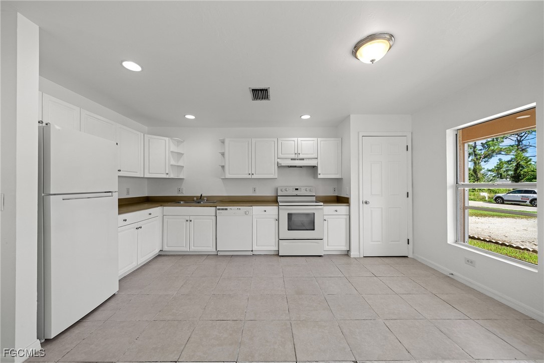 4733-4735 30th Street Southwest Lehigh Acres, FL 33973 - Photo 22 of 43 a large white kitchen with stainless steel appliances granite countertop a large counter top and a stove top oven
