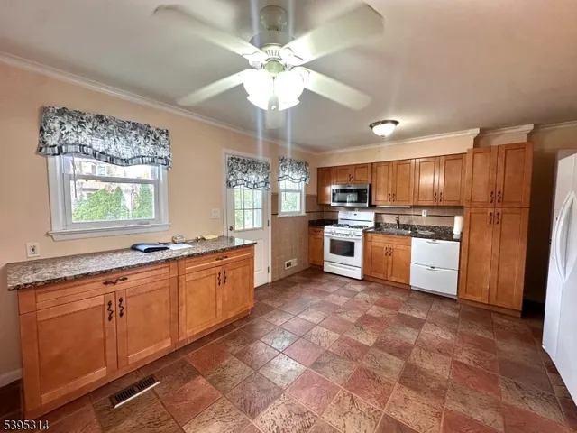 a large kitchen with stainless steel appliances granite countertop a stove sink and cabinets