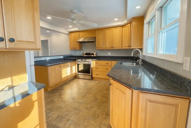 a kitchen with granite countertop a sink a counter top space and stainless steel appliances