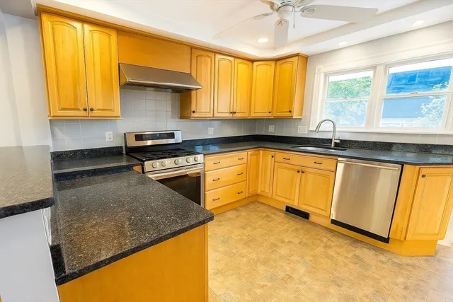 a kitchen with granite countertop a sink stainless steel appliances cabinets and a large window
