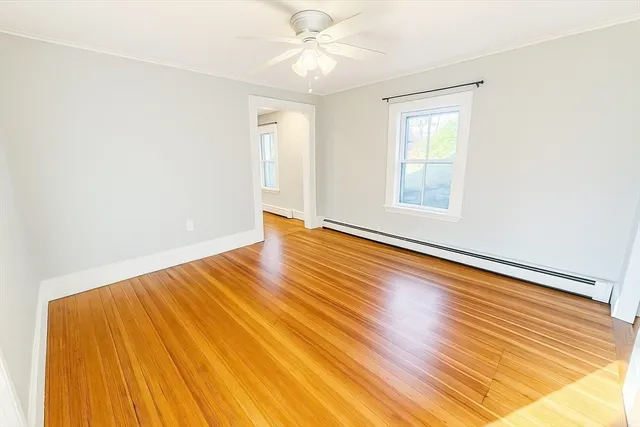 an empty room with wooden floor fan and windows
