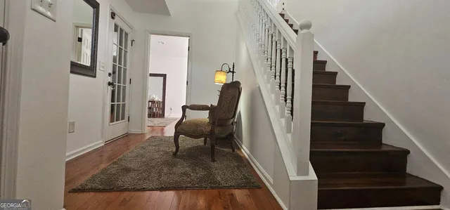 a view of a hallway to a livingroom with wooden floor and furniture