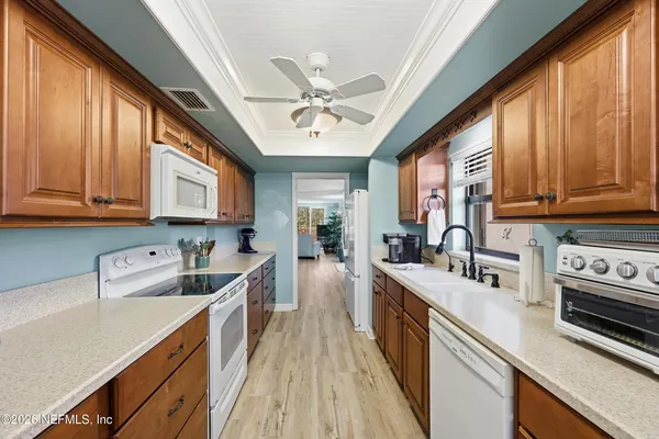 a kitchen with stainless steel appliances granite countertop a sink a stove cabinets wooden floor and a window