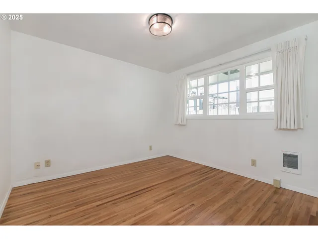 an empty room with wooden floor and fan
