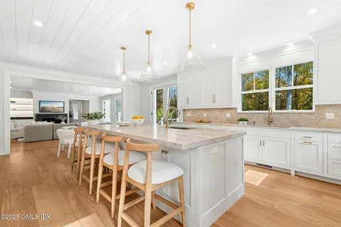 a large kitchen with kitchen island granite countertop lots of white cabinets appliances and furniture