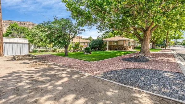 a view of a house with a yard and large trees