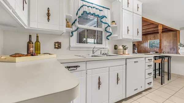 a kitchen with white cabinets and sink