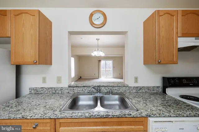a kitchen with granite countertop a sink a stove and cabinets