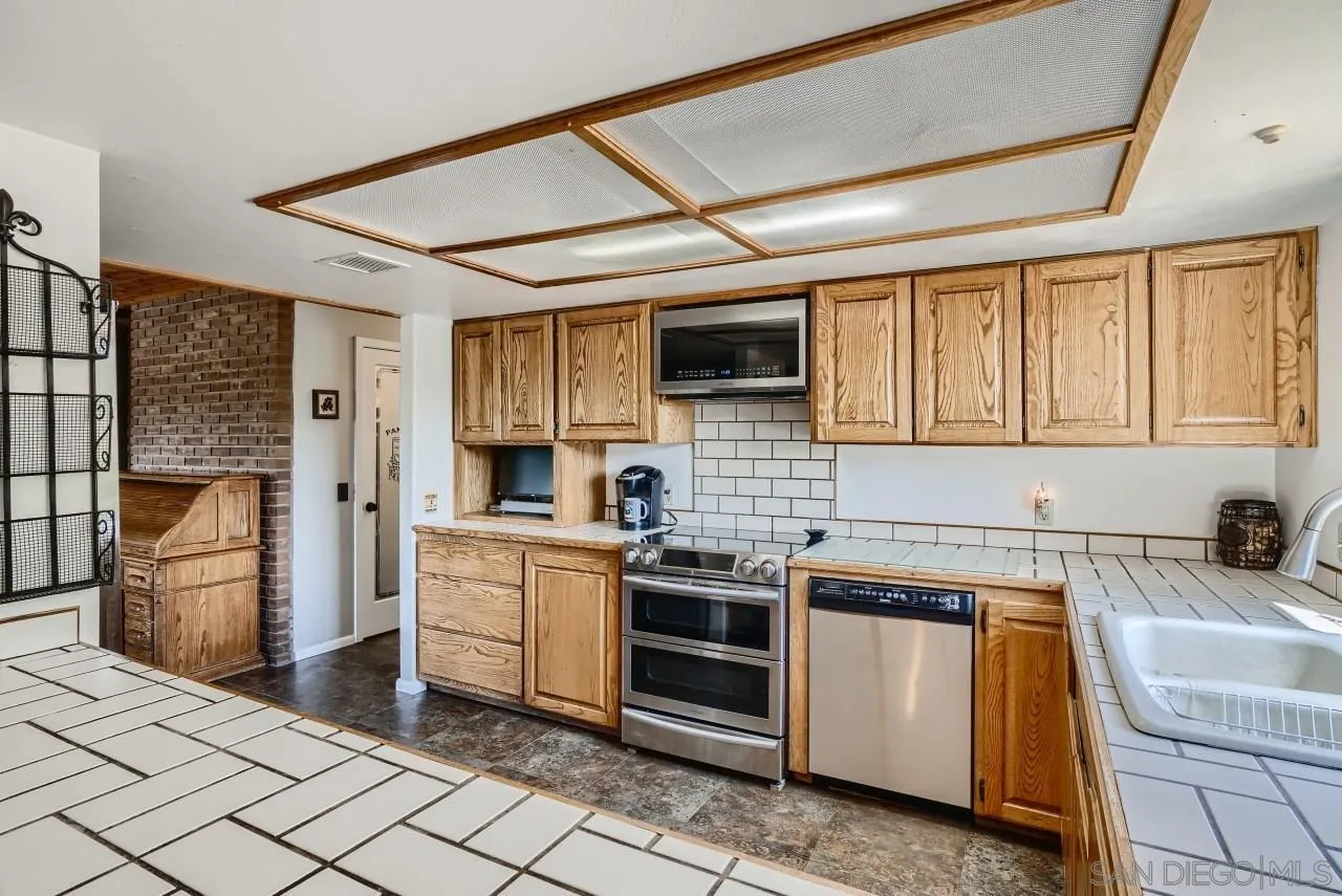 14461 Lyons Valley Road Jamul, CA 91935 - Photo 8 of 27 a kitchen with stainless steel appliances granite countertop a stove top oven a sink dishwasher a refrigerator and a cabinets with wooden floor