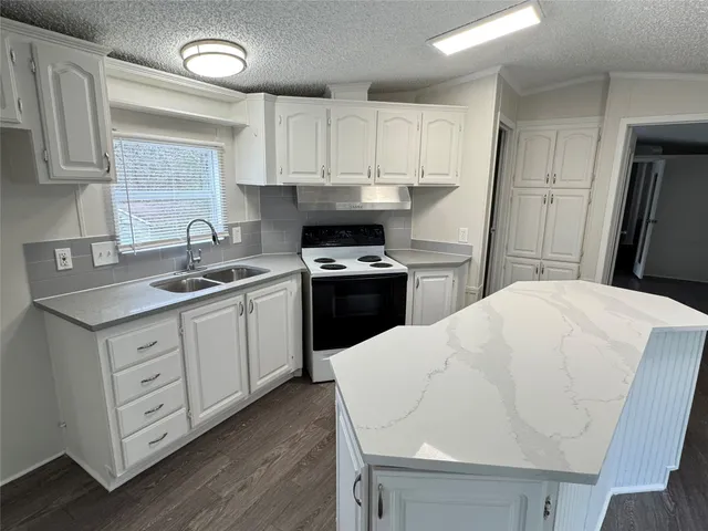 a kitchen with granite countertop wooden floors a sink and appliances