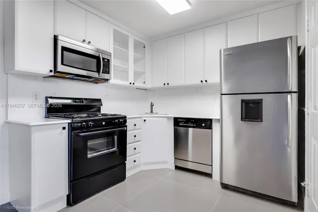 a kitchen with stainless steel appliances white cabinets white stove a microwave and a refrigerator