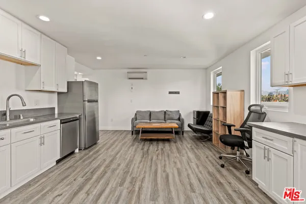 a kitchen with stainless steel appliances a stove a sink dishwasher a refrigerator and cabinets with wooden floor