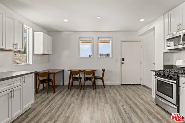 a kitchen with stainless steel appliances wooden floors and white cabinets