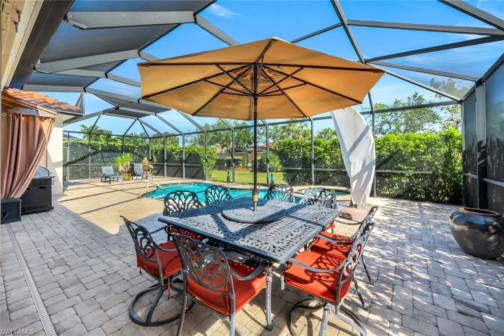 9282 Quarry Drive Naples, FL 34120 - Photo 39 of 50 a patio with a table and chairs under an umbrella
