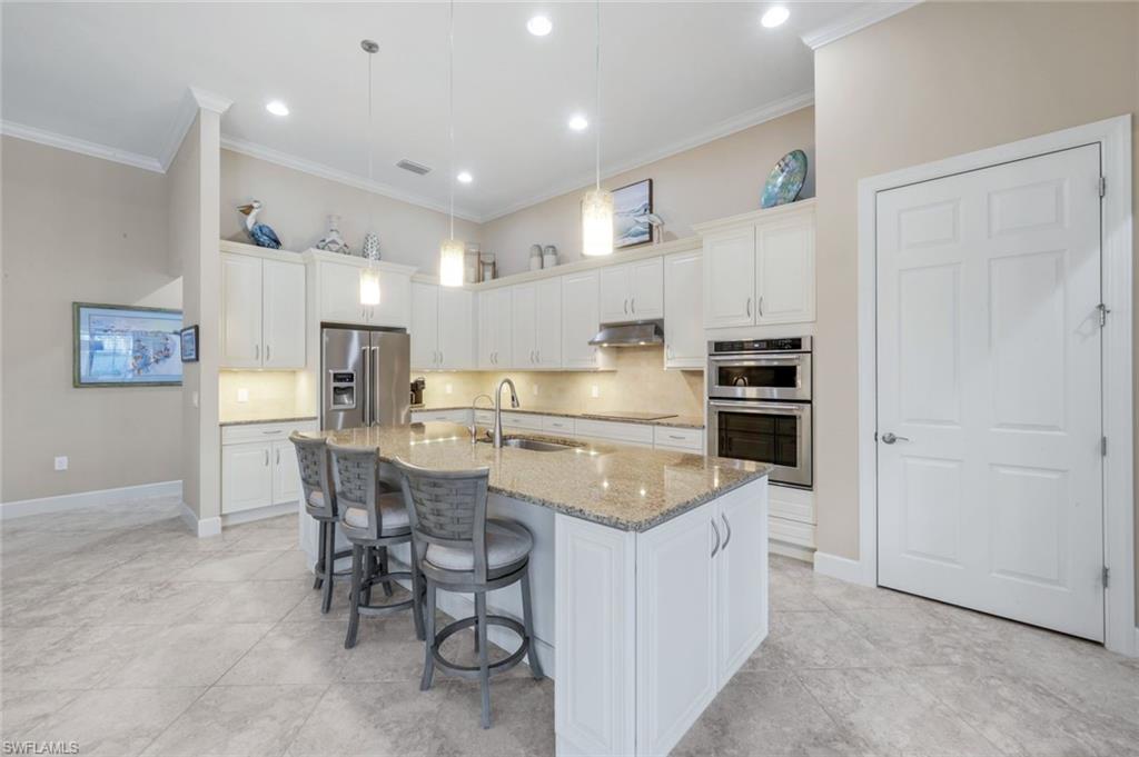 9282 Quarry Drive Naples, FL 34120 - Photo 10 of 50 a kitchen with appliances a refrigerator and chairs