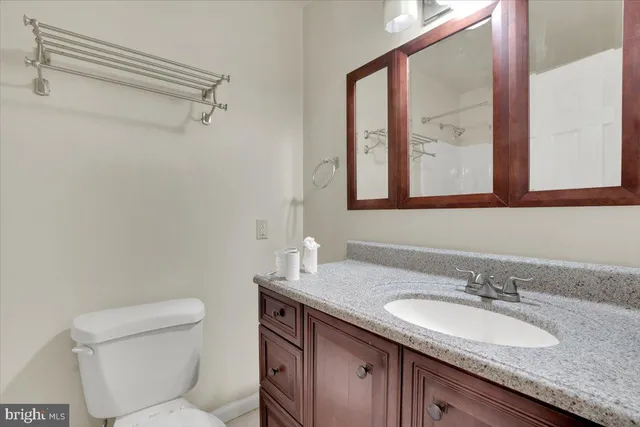 a bathroom with a granite countertop sink a large mirror a toilet and a shower