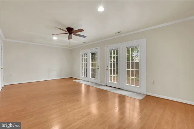 an empty room with wooden floor and chandelier fan