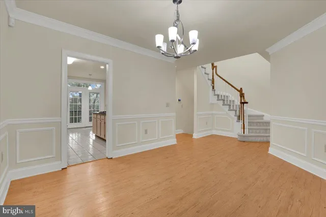 a view of an empty room with wooden floor and staircase