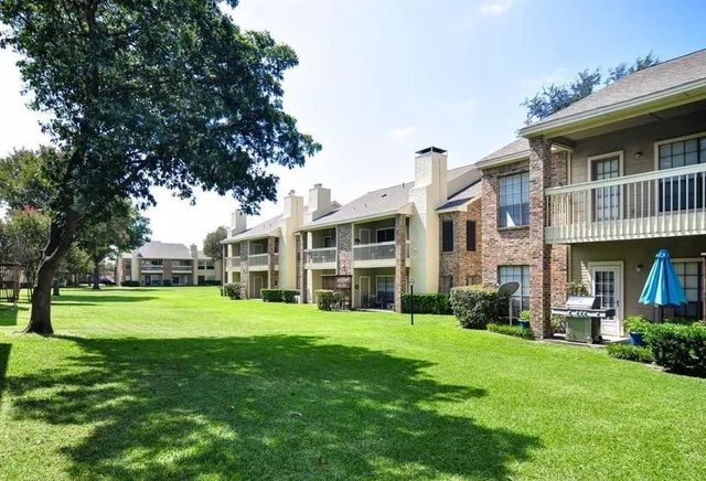 a view of a big building next to a big yard and large trees