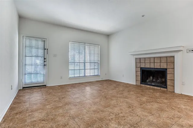 an empty room with windows and fireplace