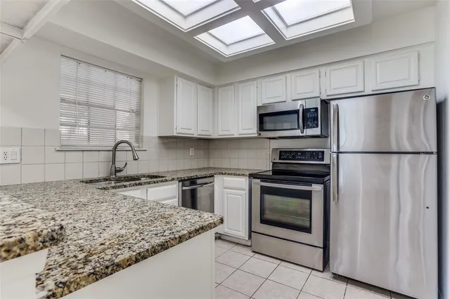 a kitchen with granite countertop a sink stove and refrigerator