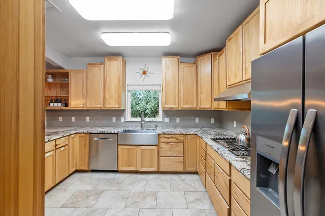 a kitchen with stainless steel appliances granite countertop a sink a stove and a refrigerator